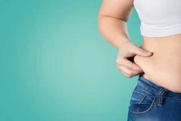 Image of woman pinching her love handles to show weight gain Brighton